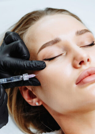 Young woman receiving plastic surgery injection on her face