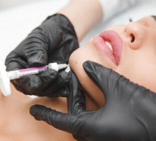 A cosmetologist makes lipolytic injections to burn fat on a woman's chin against a double chin. Women's aesthetic cosmetology in a beauty salon.The concept of cosmetology.